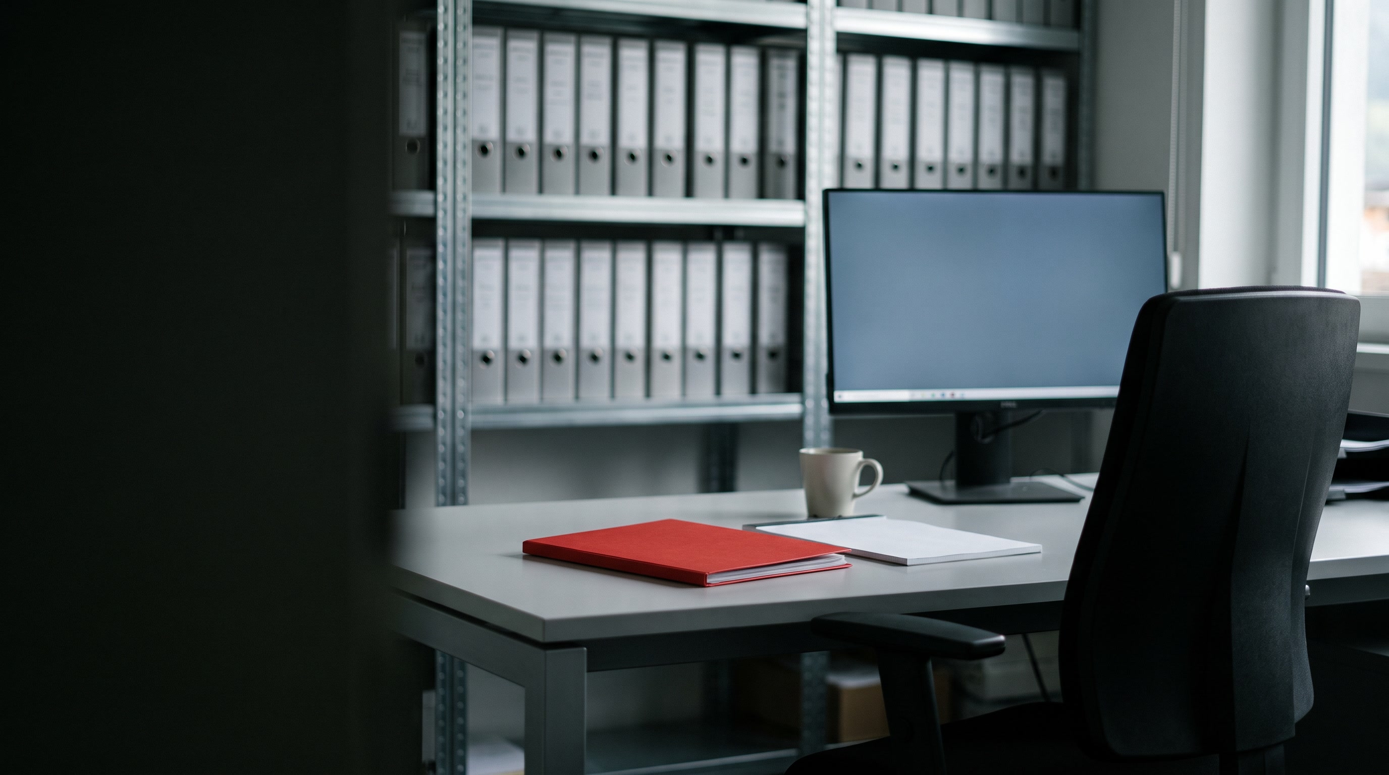 Postazione di lavoro pronta in Agenzia Dolomit: scrivania, monitor e archivio pratiche